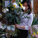 Student at flower workshop creating floral arrangement.