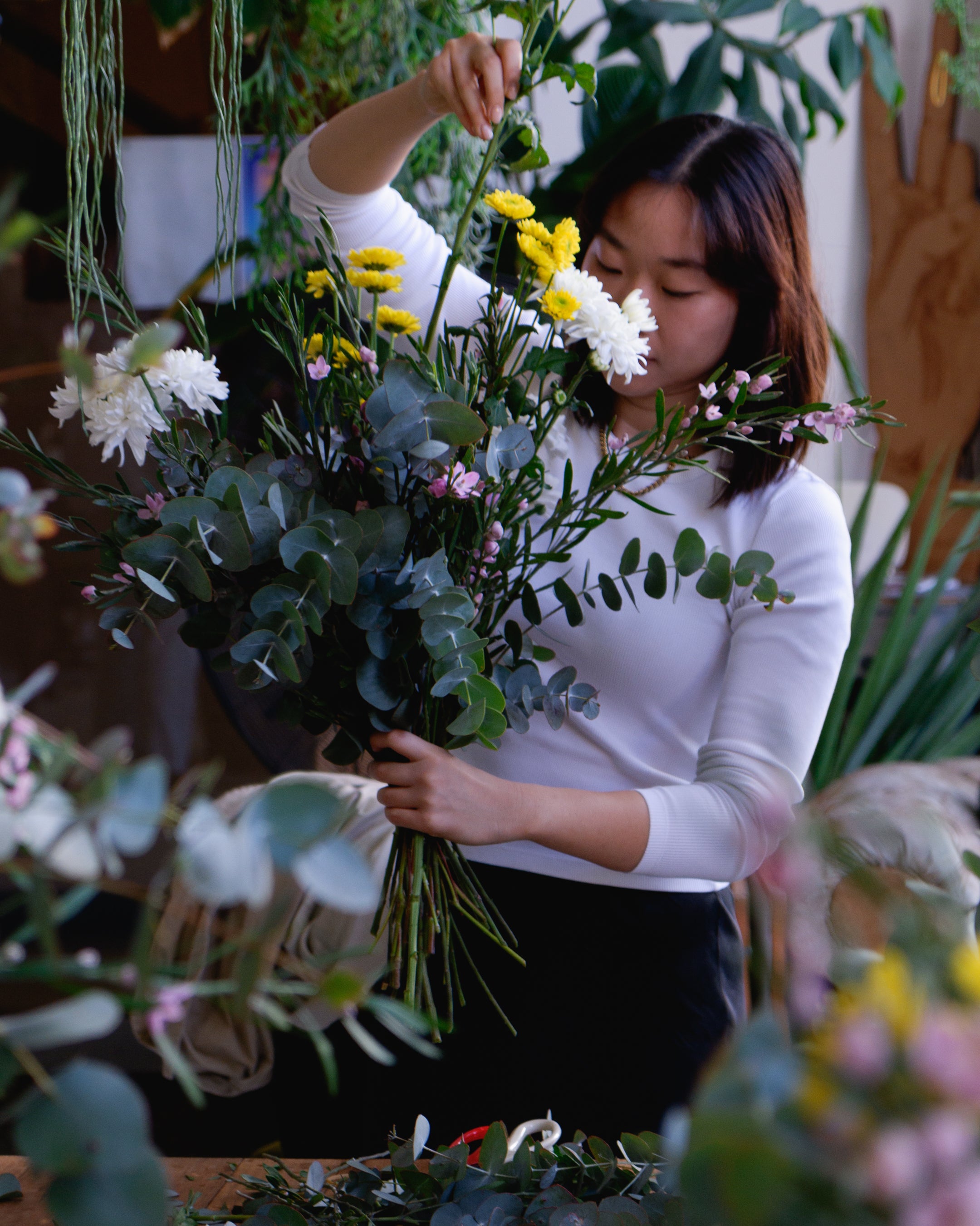 Student at flower workshop creating floral arrangement.