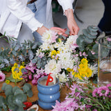 Flower workshop bench scattered with flowers and florist tools as florist give demonstration.