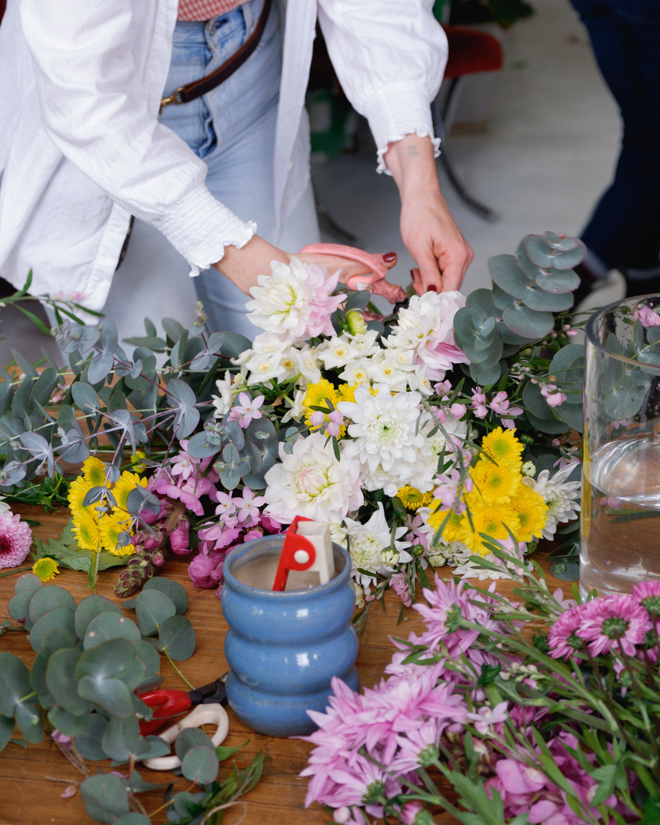 Flower workshop bench scattered with flowers and florist tools as florist give demonstration.