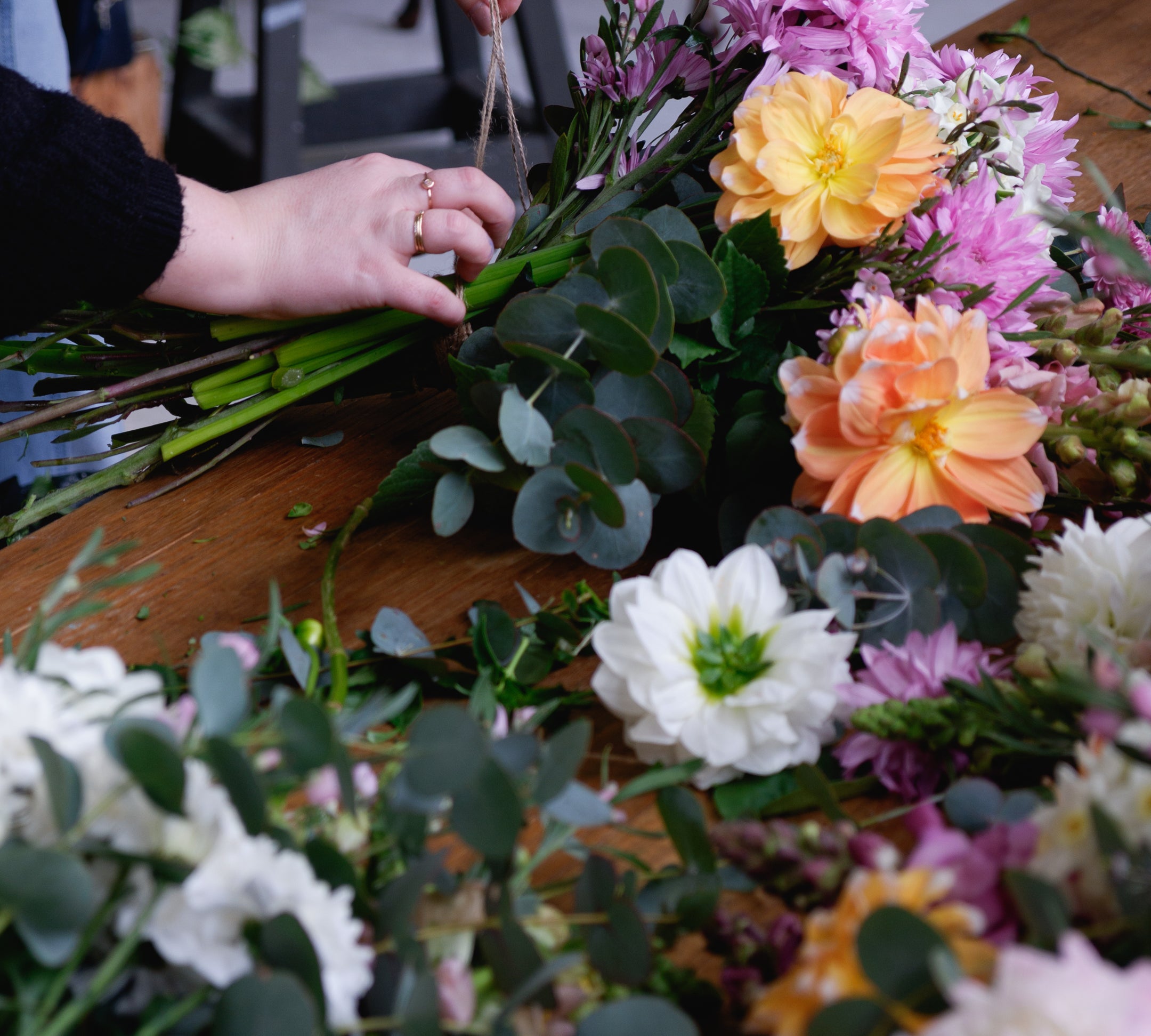 Workshop table with flowers, foliage as student ties bunch with string.