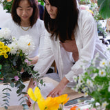 Florist teaching student at flower workshop how to wrap beautiful floral arrangement.