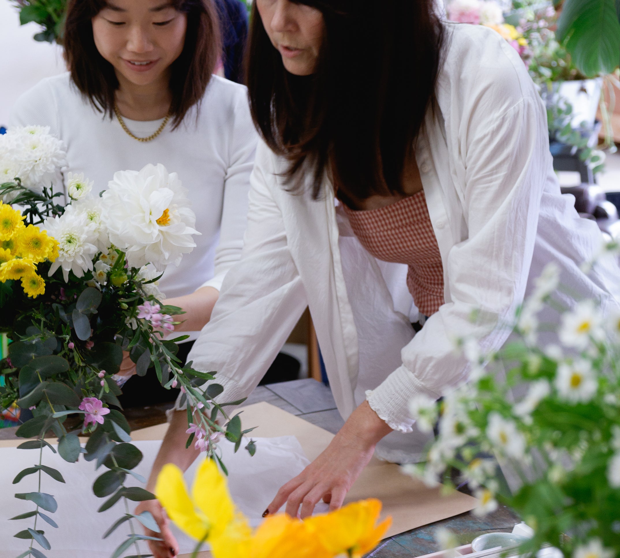 Florist teaching student at flower workshop how to wrap beautiful floral arrangement.