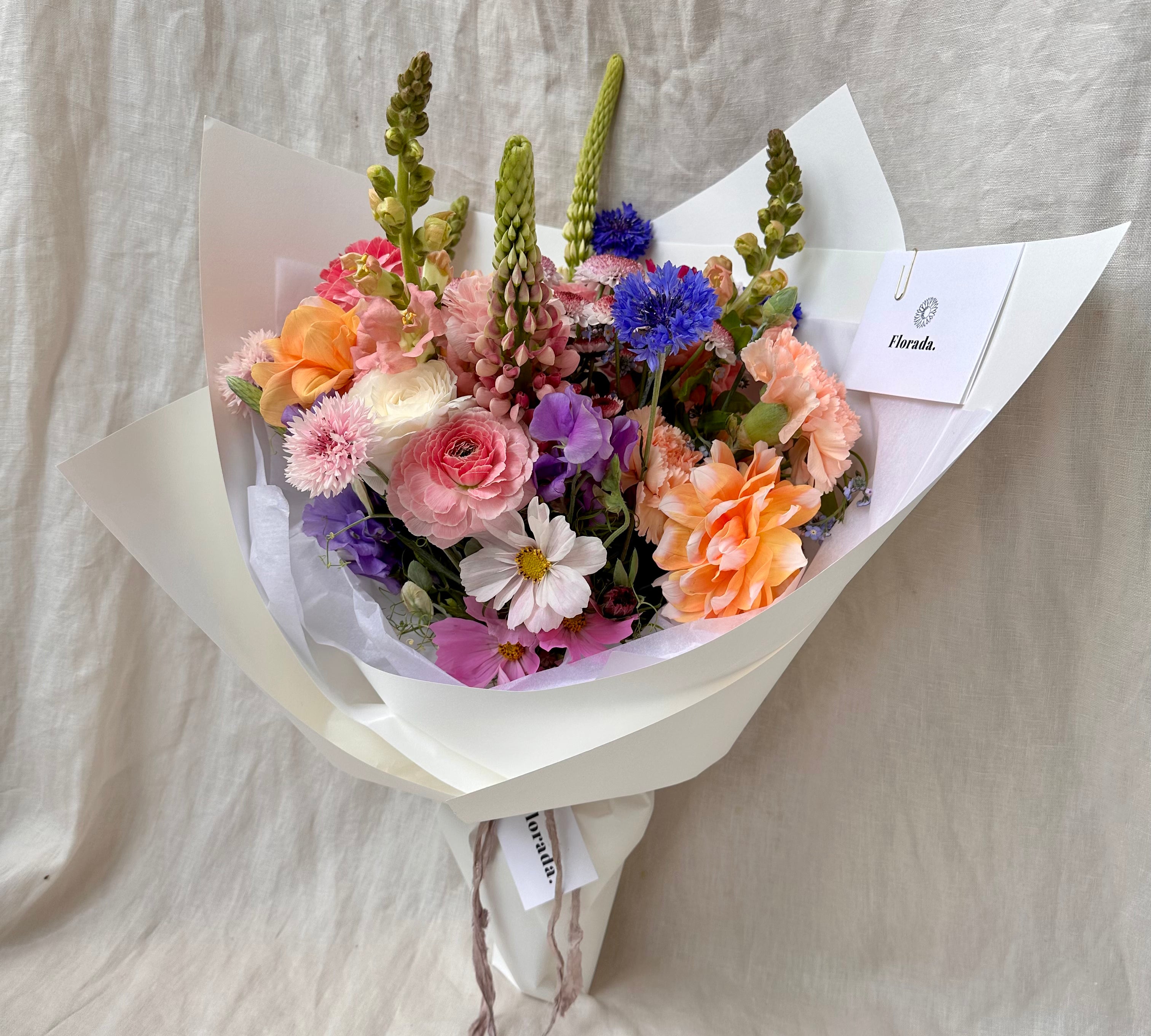 Florada floral bunch with mixed flowers as selected by florist including dahlias, ranunculus, lupins, cornflower, cosmos and carnations. 