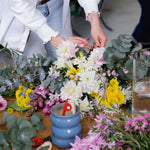 Flower workshop bench scattered with flowers and florist tools as florist give demonstration.