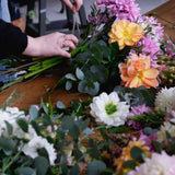 Workshop table with flowers, foliage as student ties bunch with string.