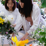 Florist teaching student at flower workshop how to wrap beautiful floral arrangement. 