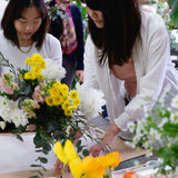 Florist teaching student at flower workshop how to wrap beautiful floral arrangement.