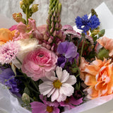 Close up image of Florada floral bunch with mixed flowers as selected by florist including dahlias, ranunculus, lupins, cornflower, cosmos and carnations. 