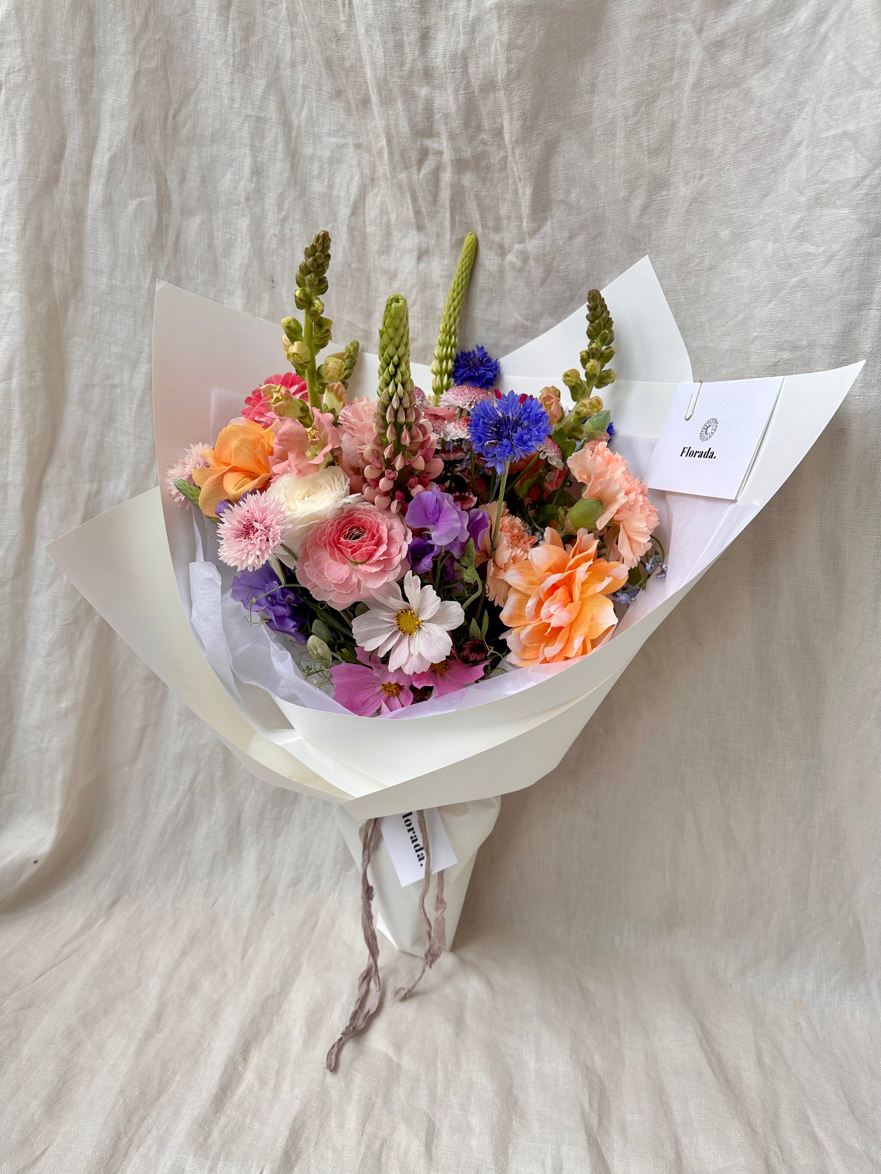 Florada floral bunch with mixed flowers as selected by florist including dahlias, ranunculus, lupins, cornflower, cosmos and carnations. 