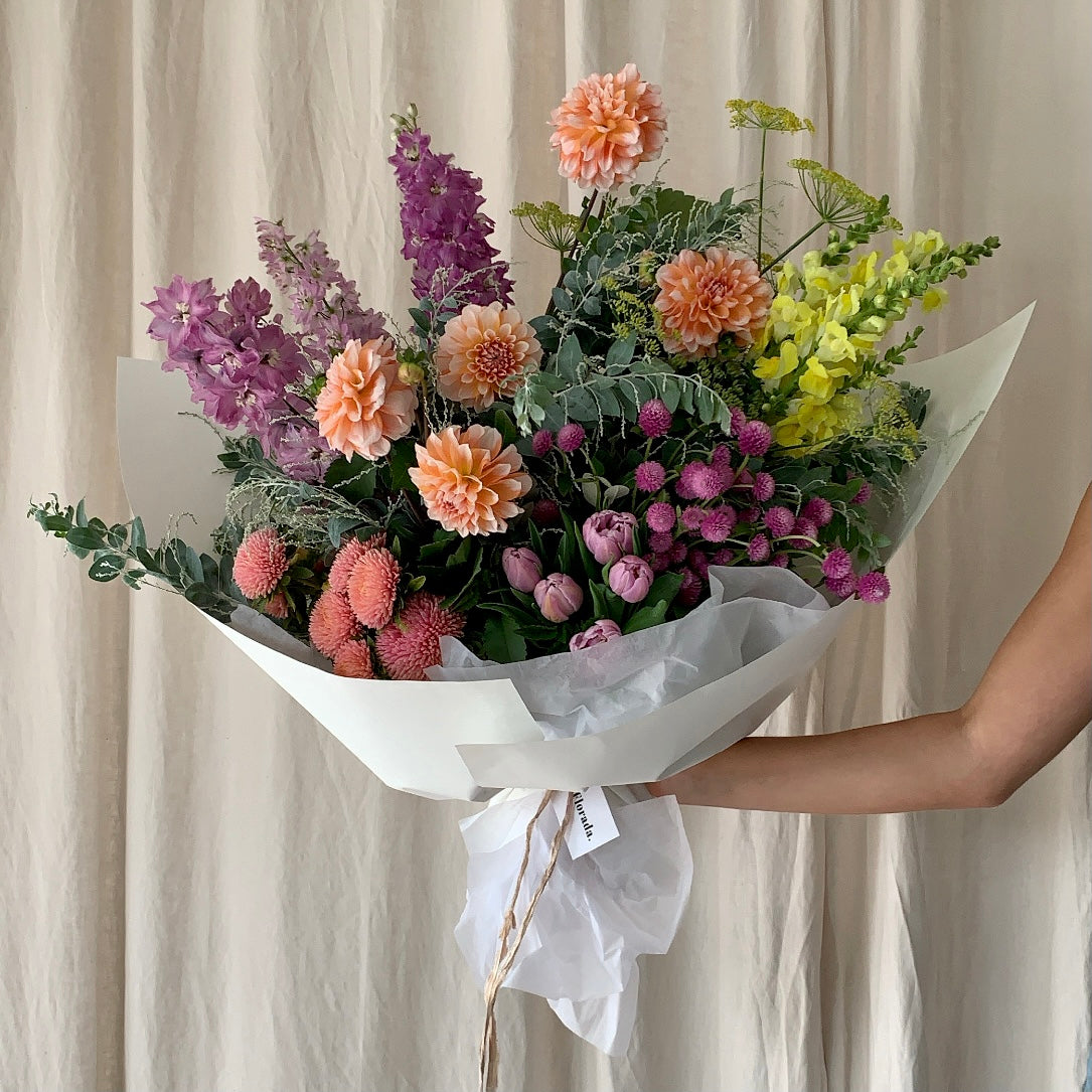 A bright and beautiful lower arrangement wrapped in low-waste wrapping paper and silk ribbon in Extravagant Gesture size. 