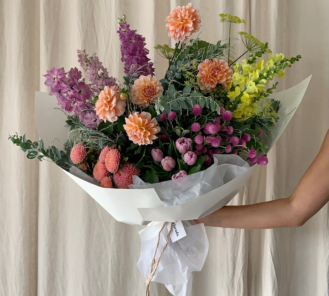A bright and beautiful lower arrangement wrapped in low-waste wrapping paper and silk ribbon in Extravagant Gesture size. 